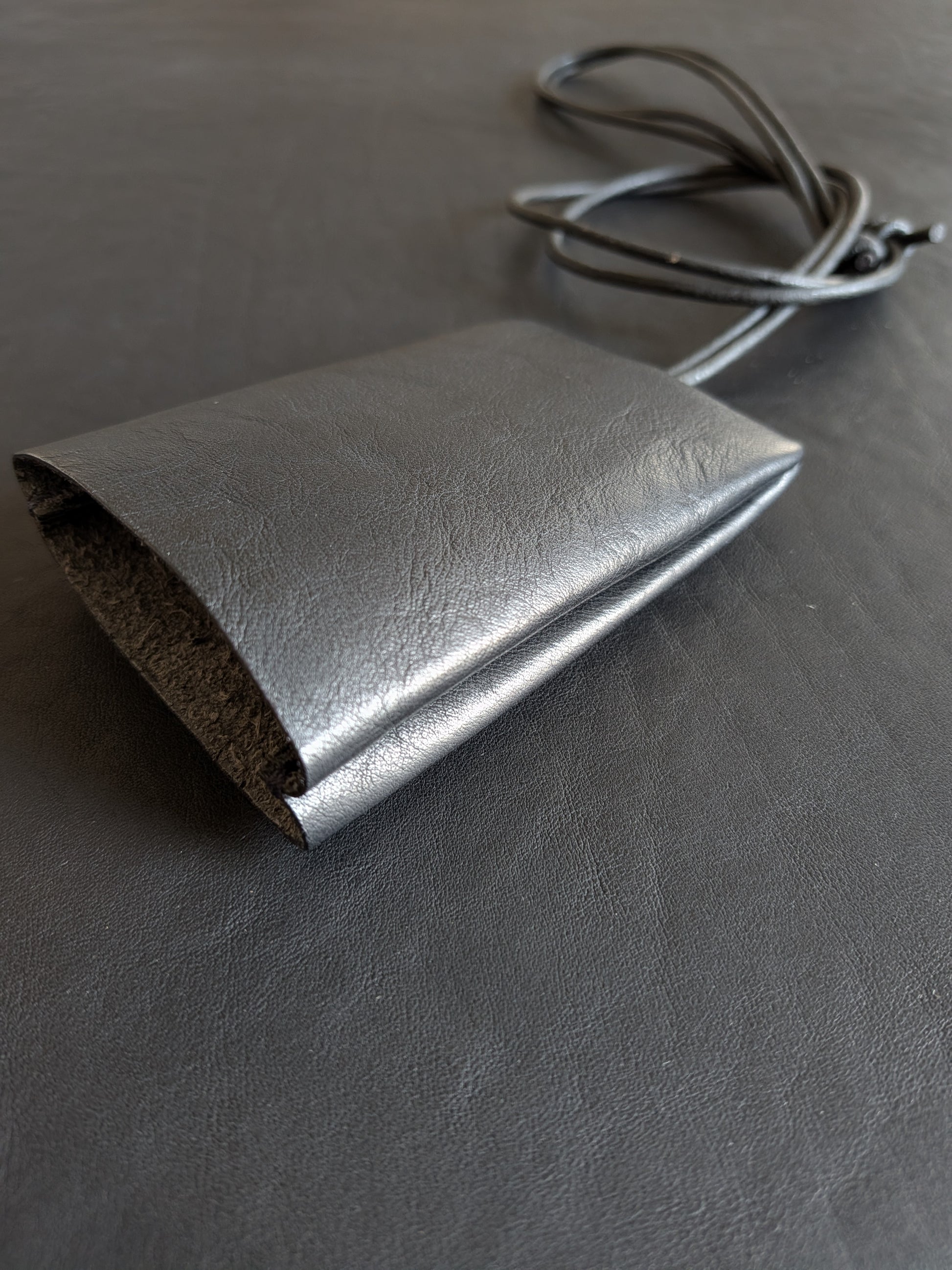 black leather pouch with a strap on a dark surface