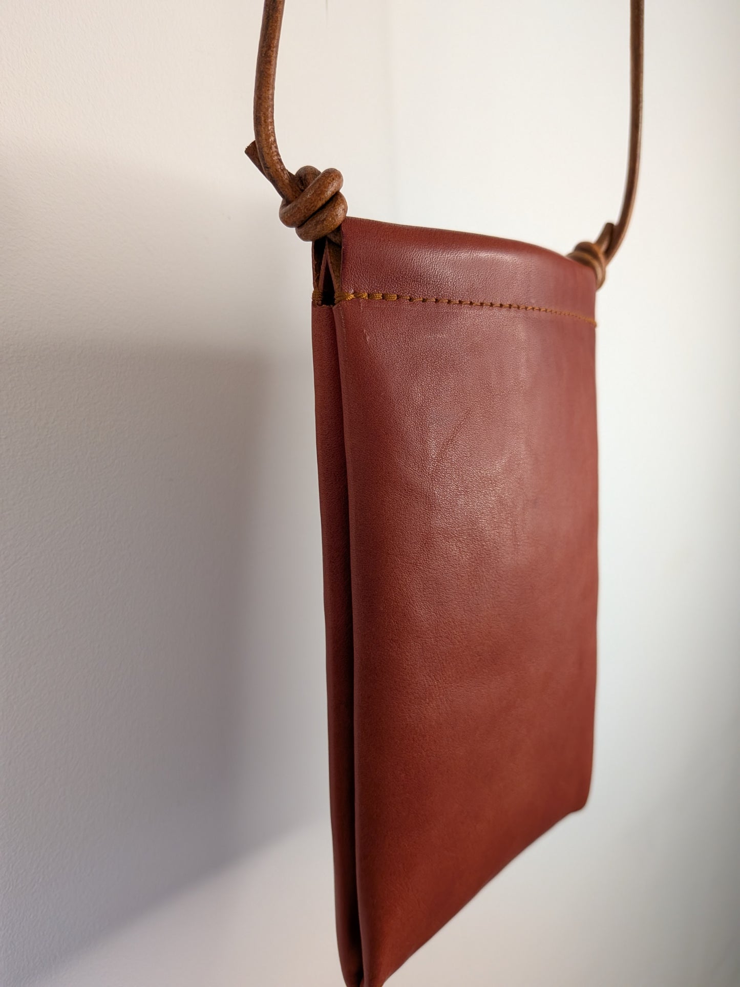 Brown leather pouch with a strap on a light gray background