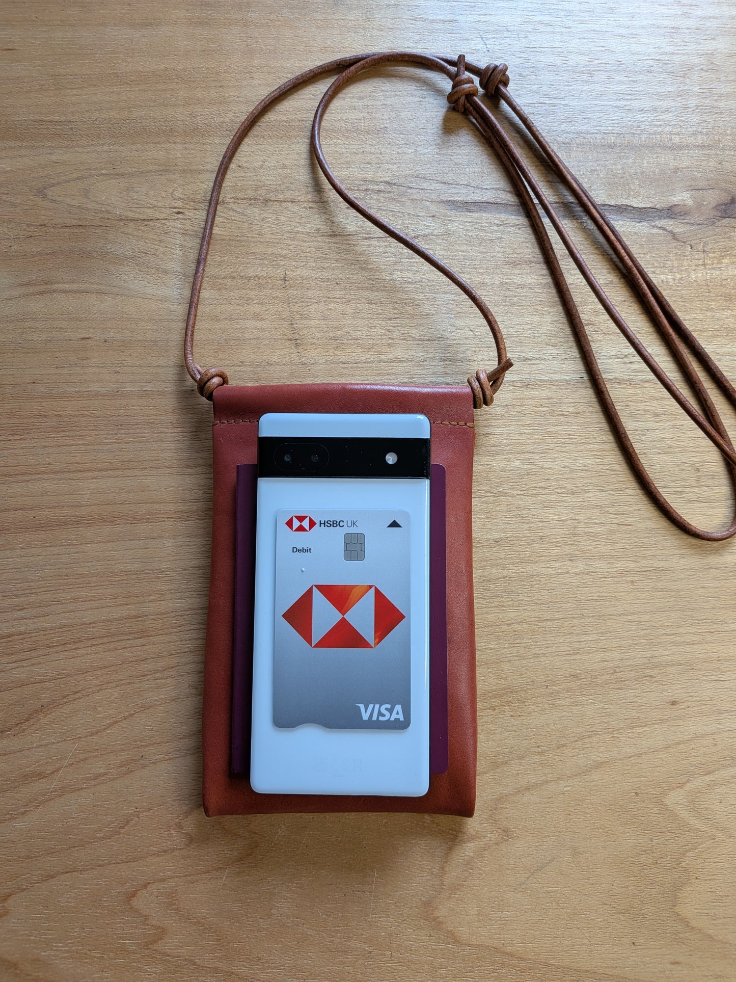 phone bag with a passport, phone and Visa card on a wooden surface